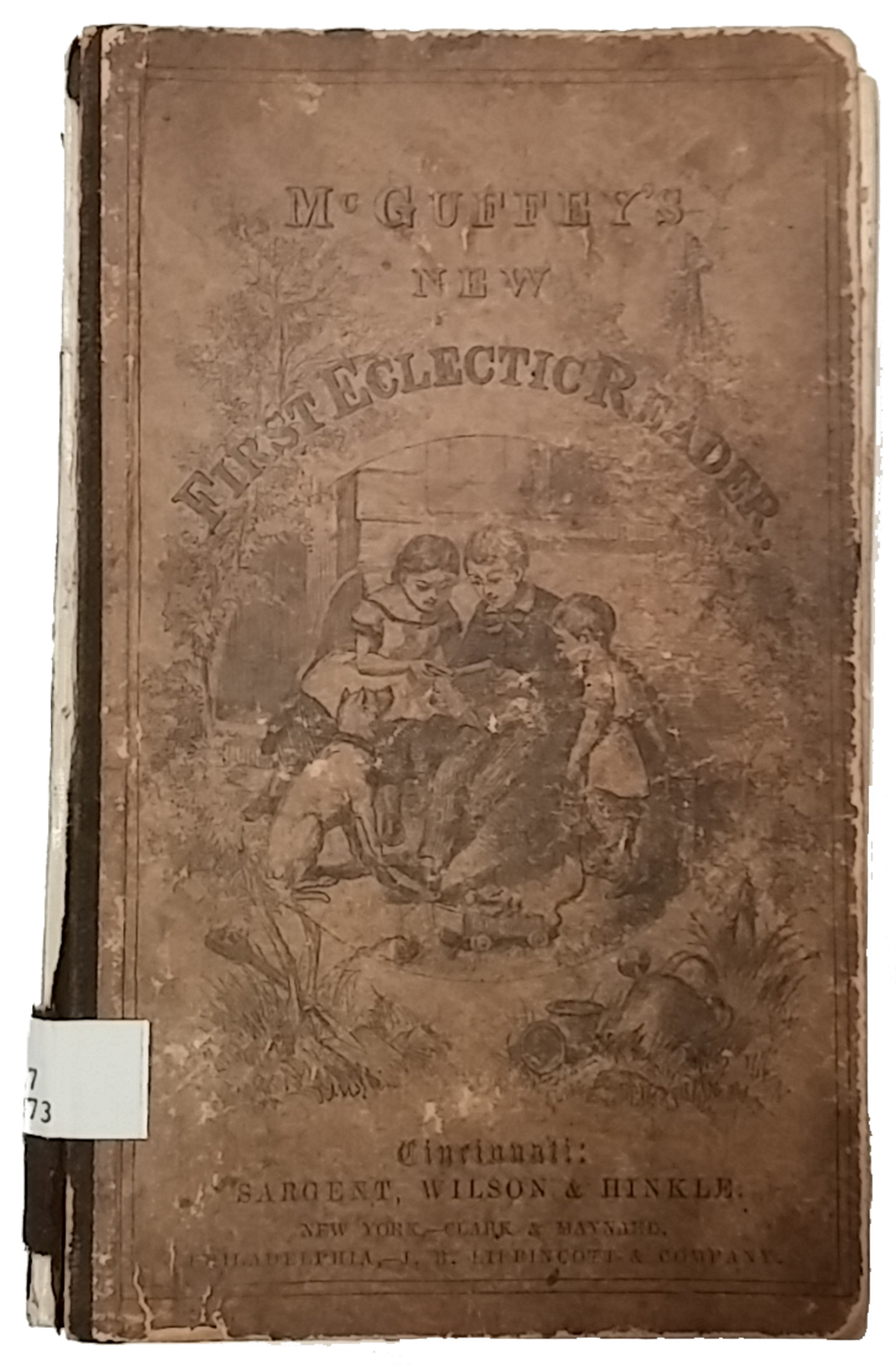 Scanned cover of McGuffey's First New Eclectic Reader. In center of cover is a black and white illustration of three children reading in a garden with a dog sitting nearby.