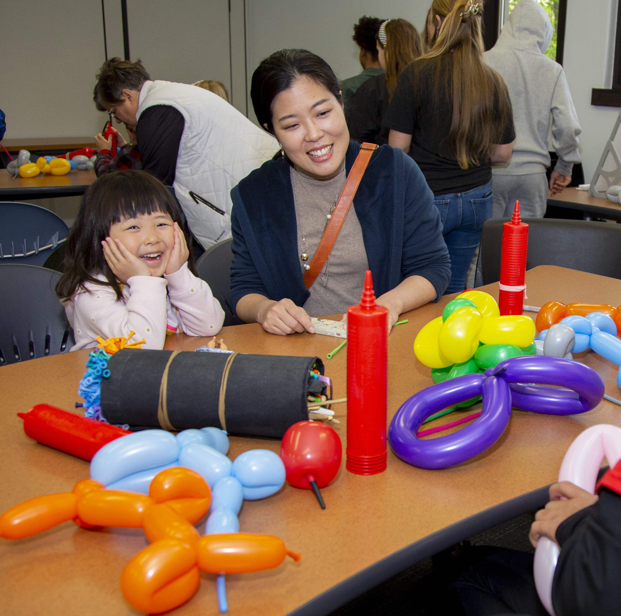 A child and her mother make balloon animals.